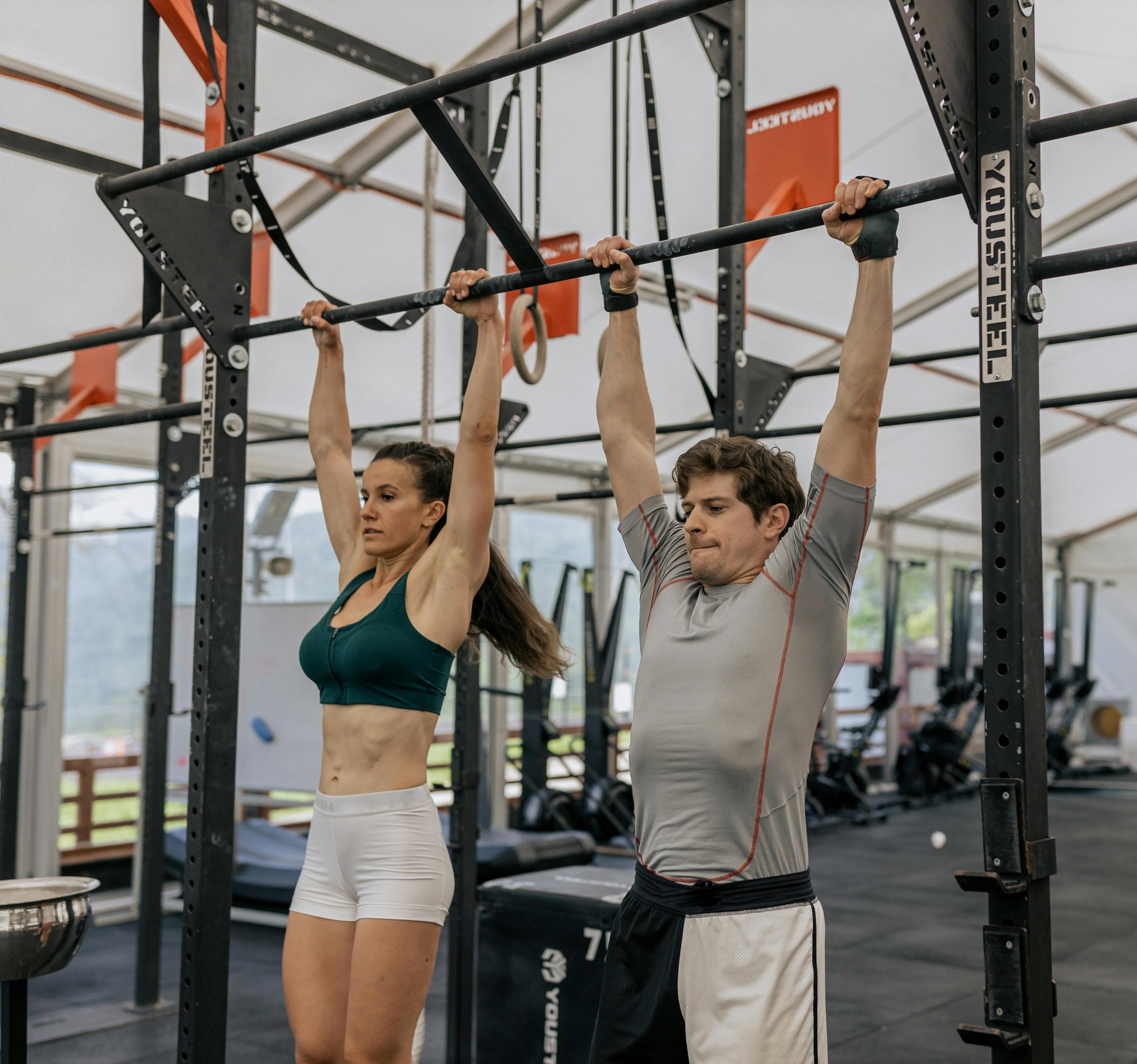 Two people doing pull-ups in gym